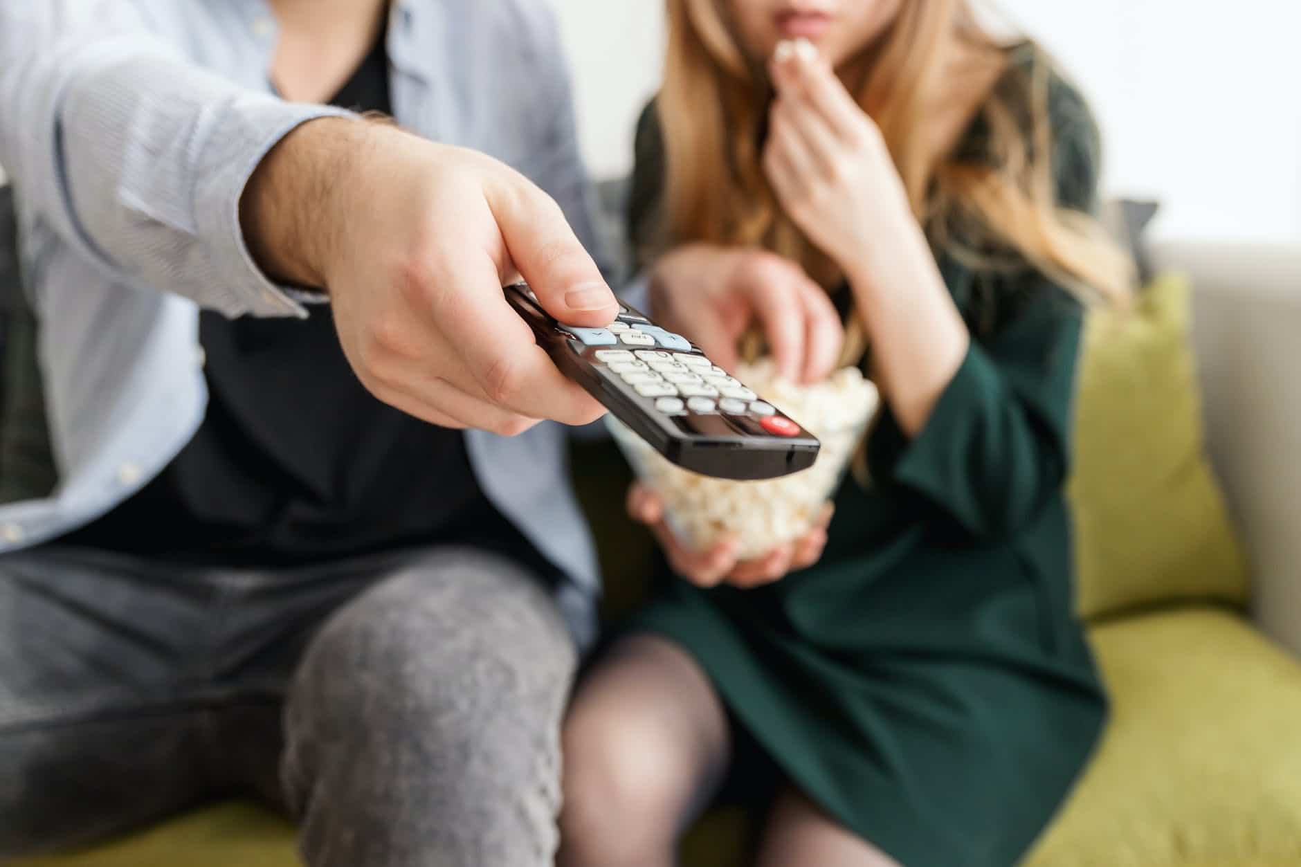 uma criança comendo pipoca e seu pai controlando a televisão para assistir filme sobre vinhos