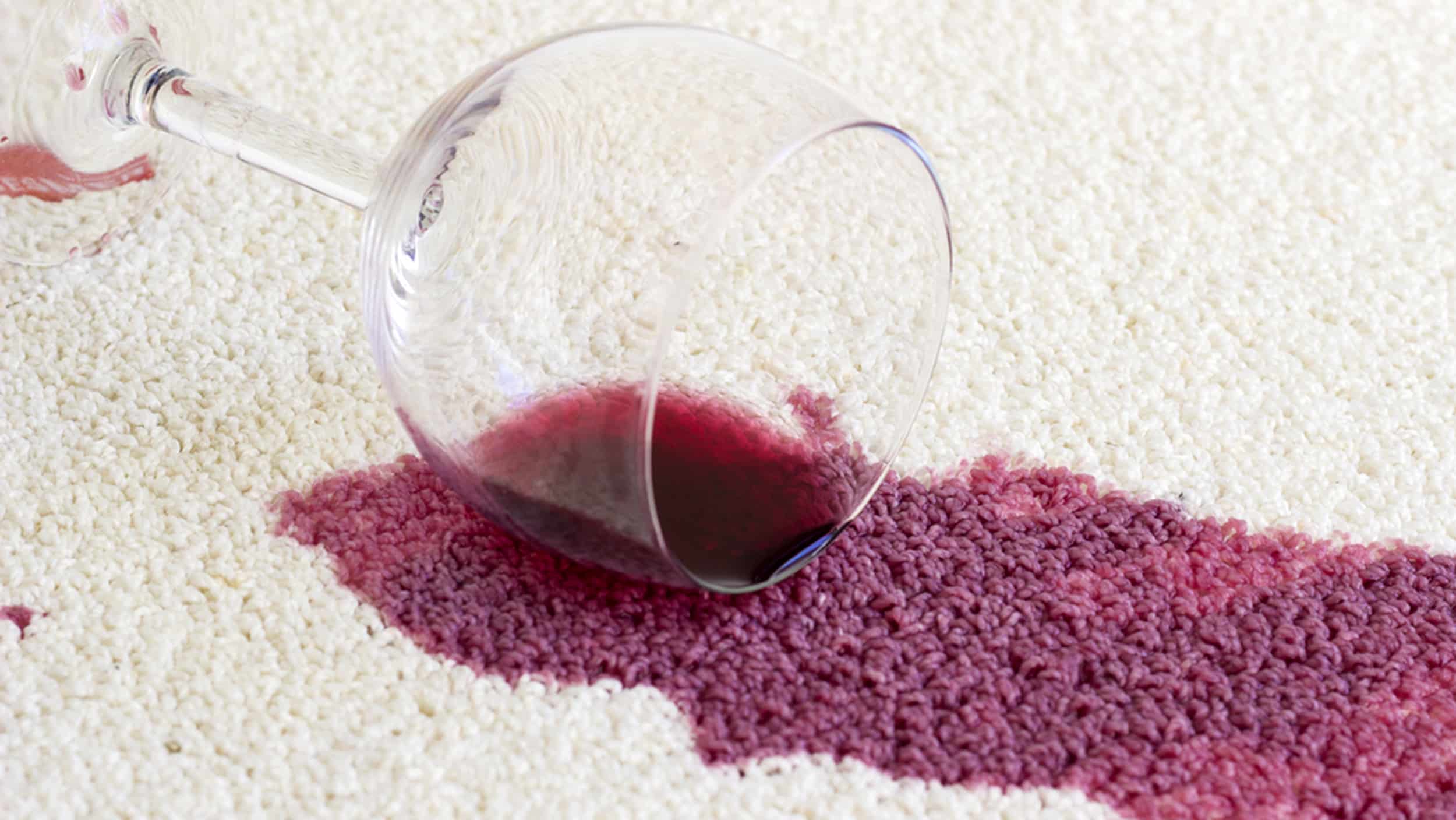 Taça de vinho derramada em um tapete branco