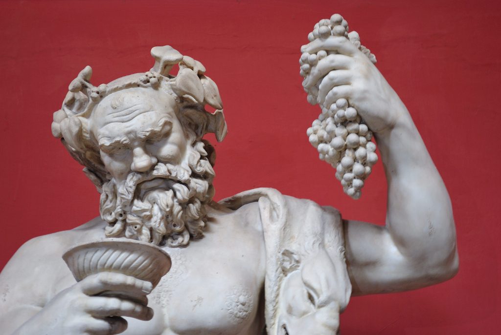 Estátua antiga de um deus do vinho tomando vinho