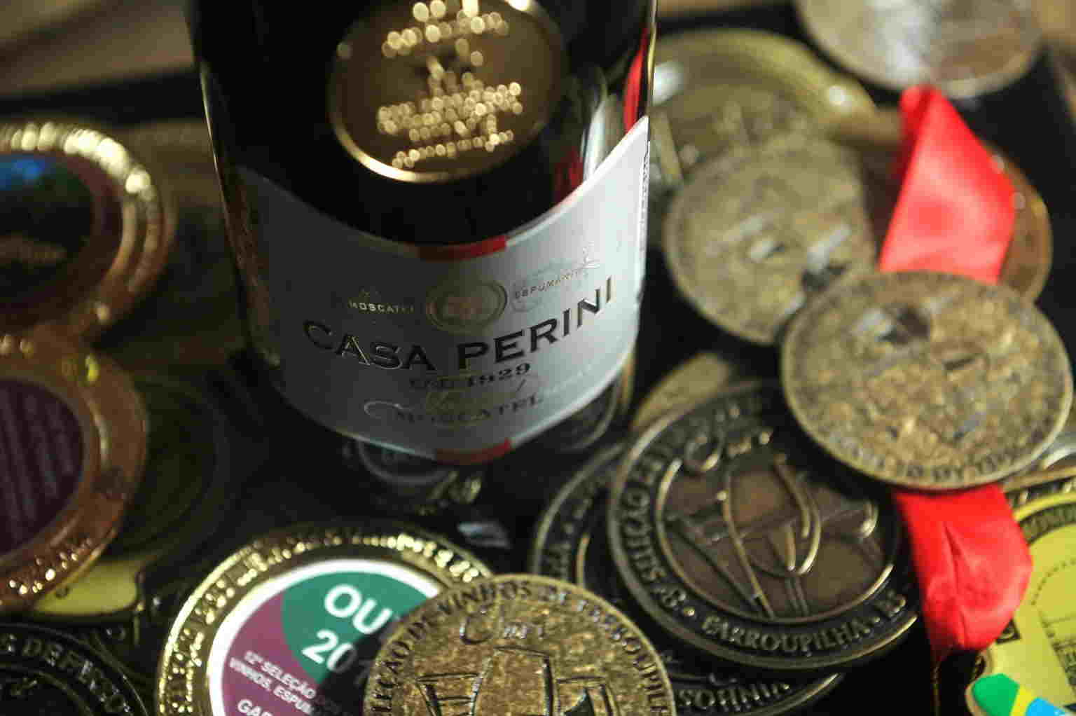 Garrafa de vinho moscatel cercada por medalhas