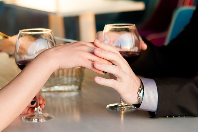 casal dando as mãos enquanto tomam vinho